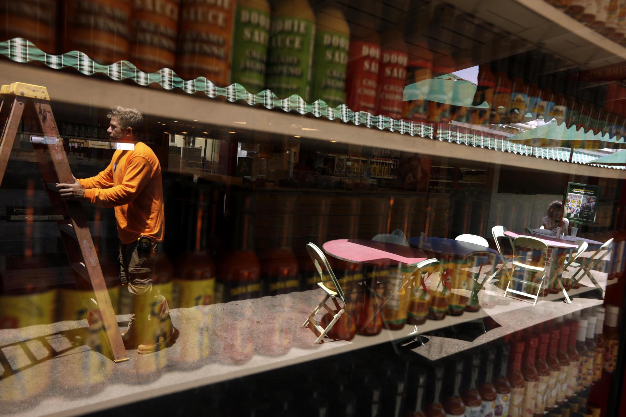 A worker is reflected in the storefront window of a store 