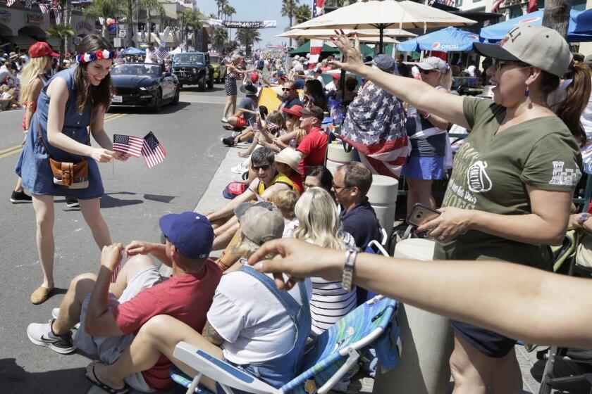 Brana Vlasic hands out American Flags during the Fourth of July Parade in 2019 in Huntington Beach.