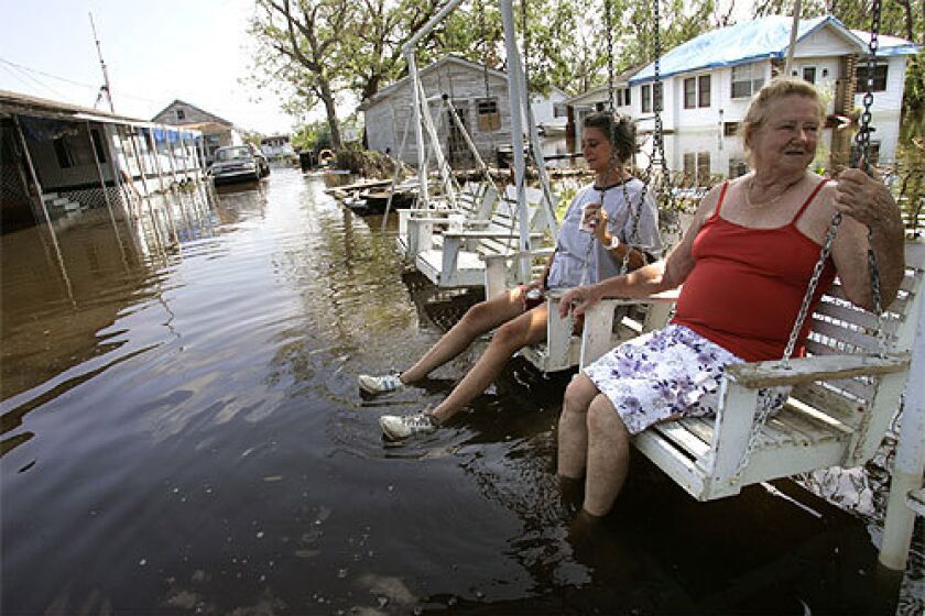 COOLING OFF: Elda Matherne, right, and friend Bridget Smith dip their feet in floodwater in front of Matherne's home in Barataria, La., south of New Orleans. Water was 2 feet deep in many houses in Jefferson Parish, and much of the region remained without power.