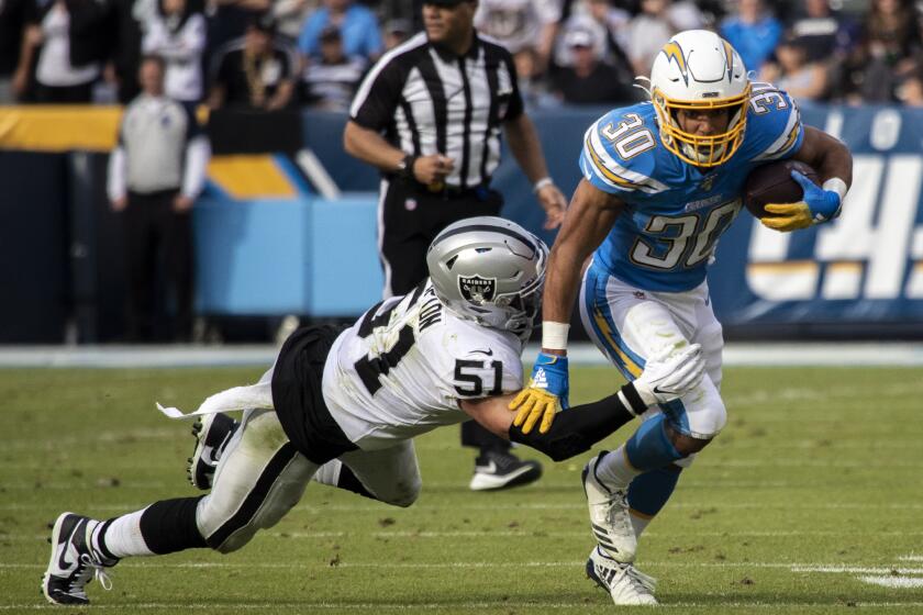 CARSON, CALIF. -- SUNDAY, DECEMBER 22, 2019: Los Angeles Chargers Los Angeles Chargers running back Austin Ekeler (30) evades a tackle by Oakland Raiders Oakland Raiders inside linebacker Will Compton (51) in 2nd quarter during game at Dignity Health Sports Park in Carson, Calif., on Dec. 22, 2019. (Brian van der Brug / Los Angeles Times)