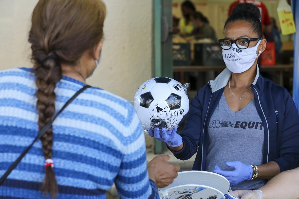 Renata Simril, of LA84 Foundation, distributes sports goods to under-served kids, at LAUSD Grab and Go meal center at Thomas Alva Edison School on Wednesday in Los Angeles.