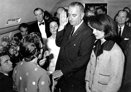 Jack Valenti, rear left, watches Vice President Lyndon B. Johnson take the presidential oath of office aboard Air Force One after the assassination of President John F. Kennedy. Valenti was a media aide to Johnson at the time.