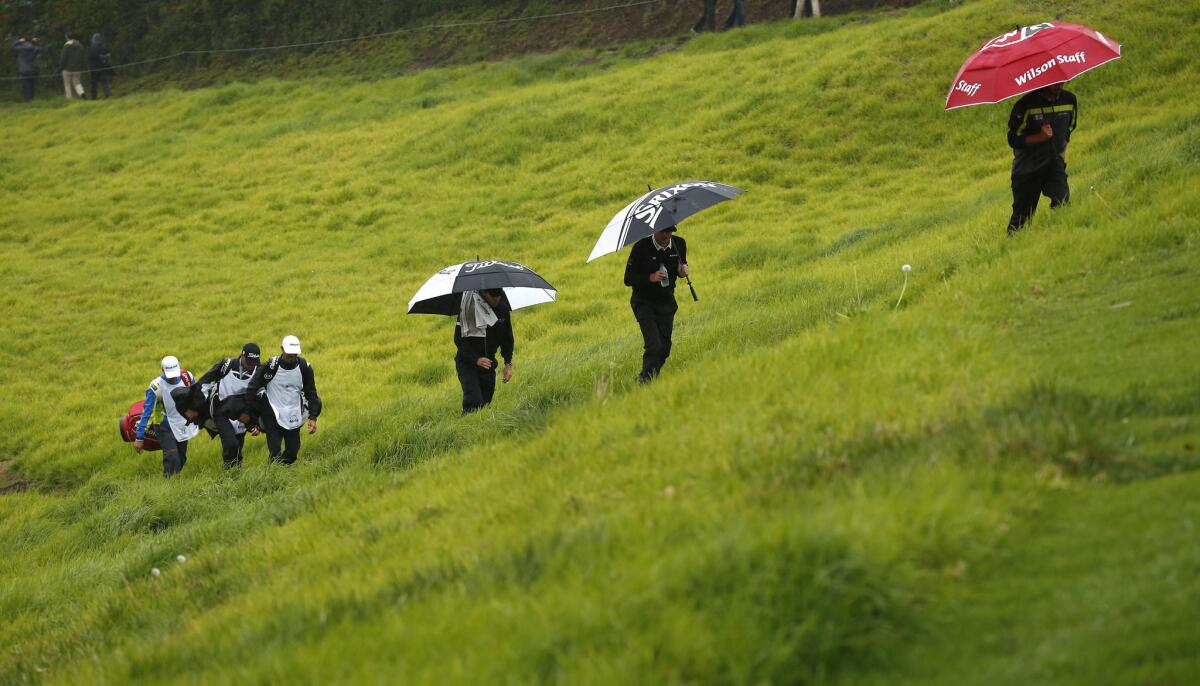 Golfers take cover from the rain during the second round of the Genesis Open at the Riviera Country Club in Pacific Palisades on Friday.