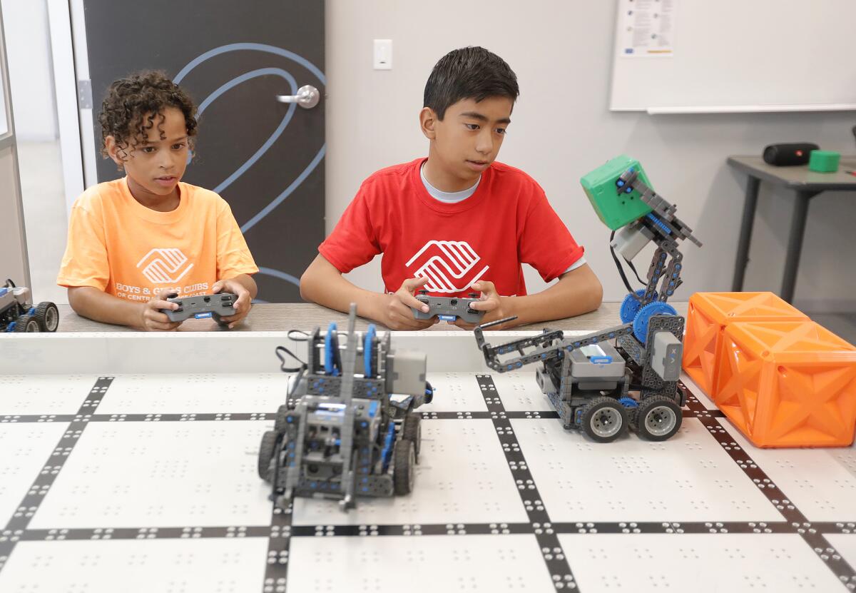 Maxwell Grant and Garold Kraft, from left, move objects around with robots.