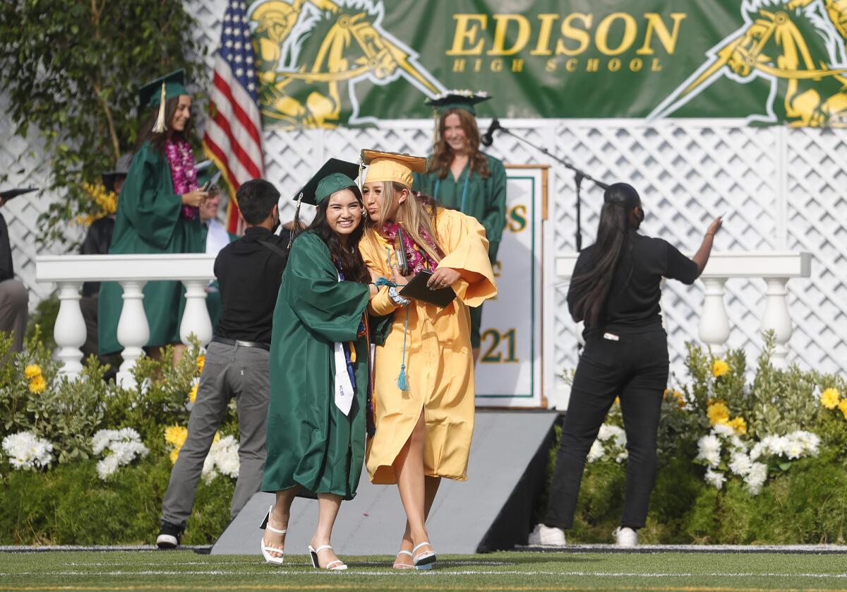 Two friends walk together after receiving their diplomas at the 2021 Edison High graduation ceremony.