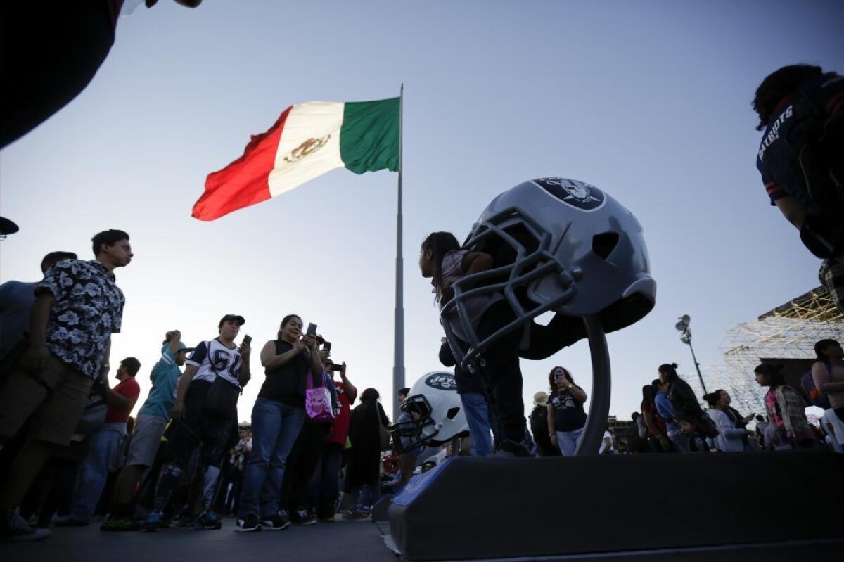 A girl poses for a photograph with a large Raiders helmet at the NFL Fan Fest in Mexico City on Nov 19..