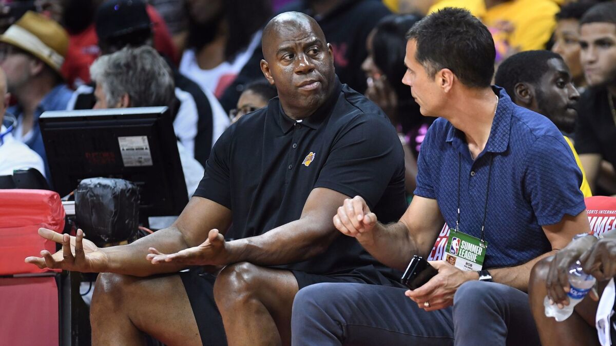 Lakers president of basketball operations Magic Johnson and general manager Rob Pelinka sit courtside at Thomas and Mack Center for the Summer League opener against the Clippers.