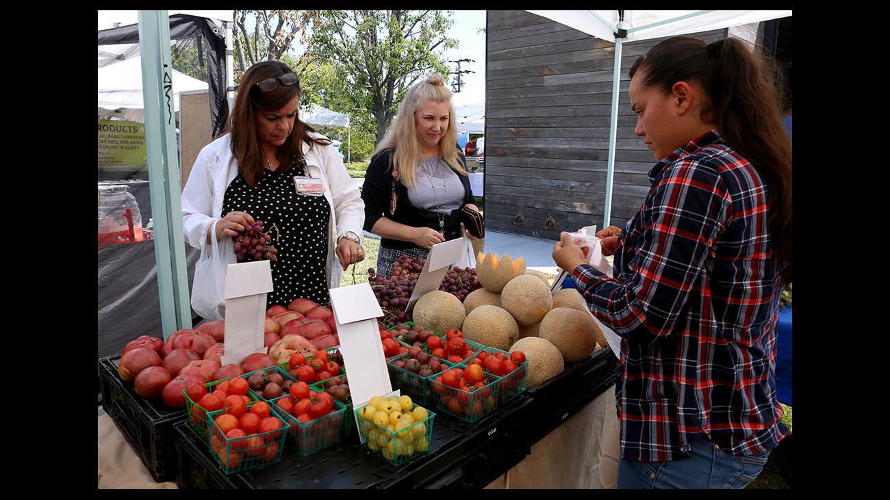 Wendy Katsiotis, left, and Julianne Courtenay, right, grab some fresh fruit from the Devine Harvest stand, with Maria Garcia, right, helping, at the St. Joseph Medical Center Farmers Market, in Burbank on Tuesday, July 17, 2018. The market began one week ago and goes from 9am to 2 pm, every Tuesday. Eight vendors offered customers fresh fruit and vegetables, to cold fresh fruit drinks and a variety of foods like tacos, fresh roasted peanuts, pupusas, bulgogi burgers, hummus, cobblers, a variety of dips, baba ghanoush and pita bread.
