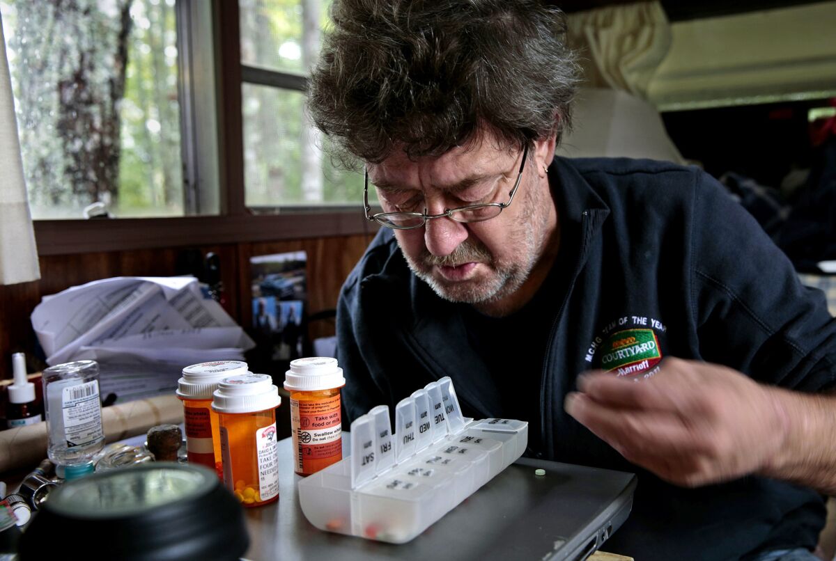 David Smith looks over his daily medications. He gets help with organizing his medicines when nurse Sally Patterson visits.