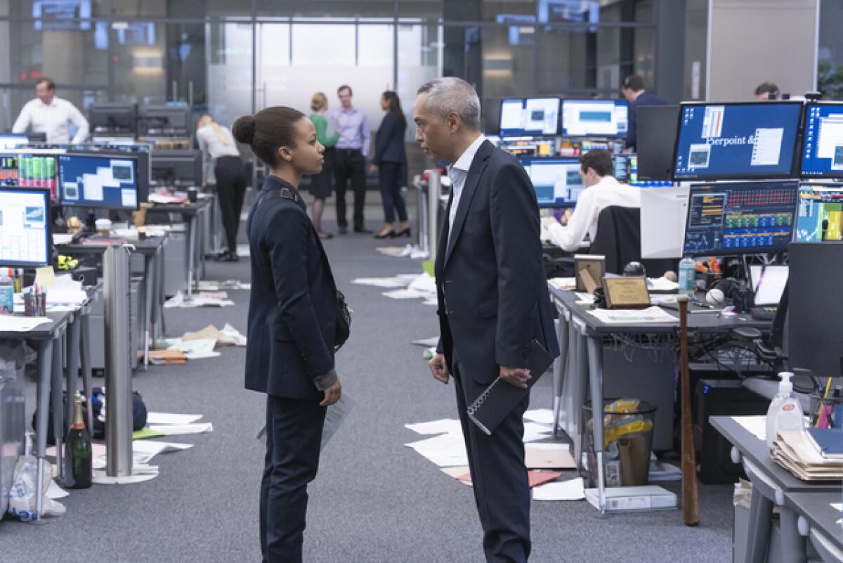 A young woman and an older man face off on a trading floor