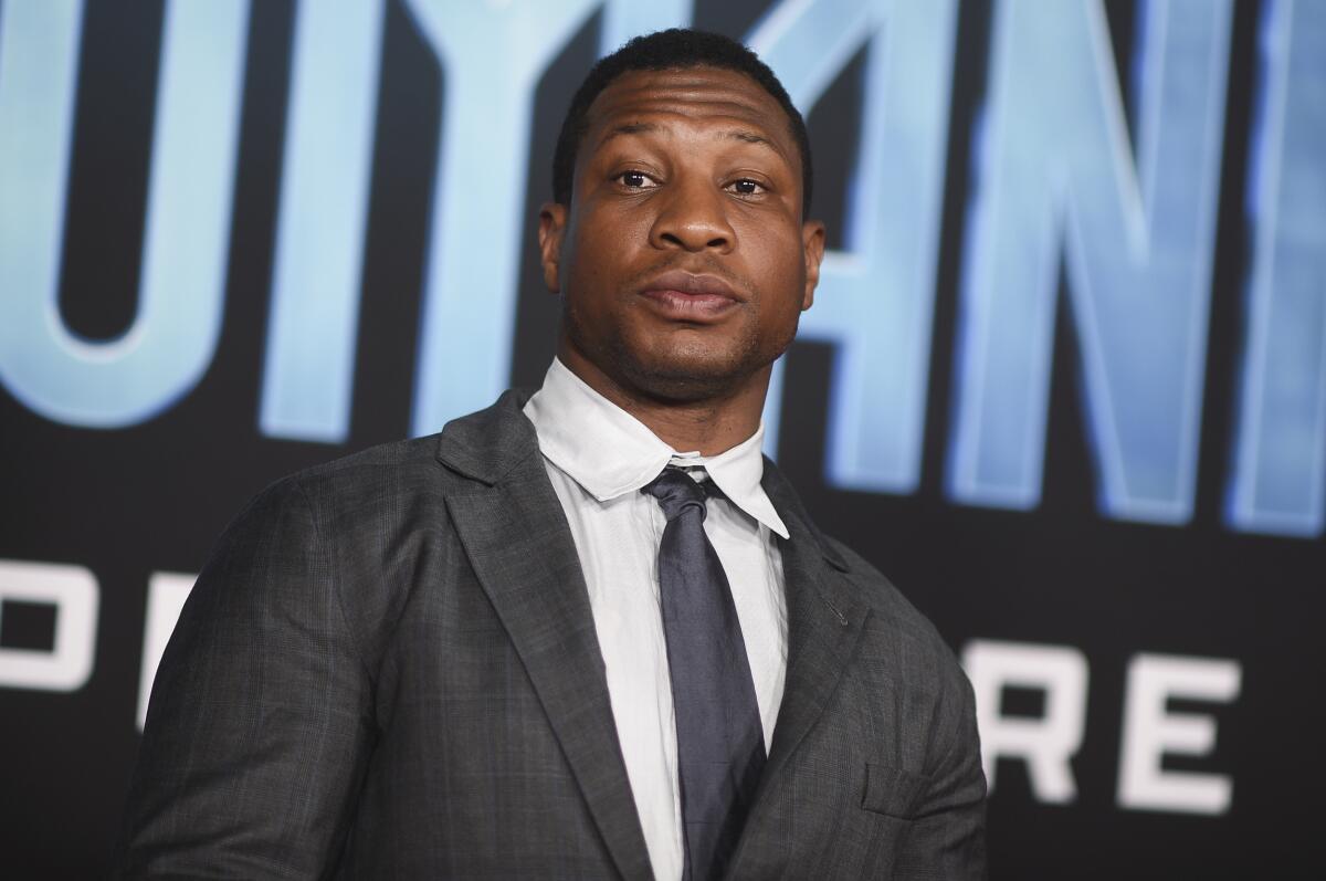 A man with short black hair posing in a gray suit and tie