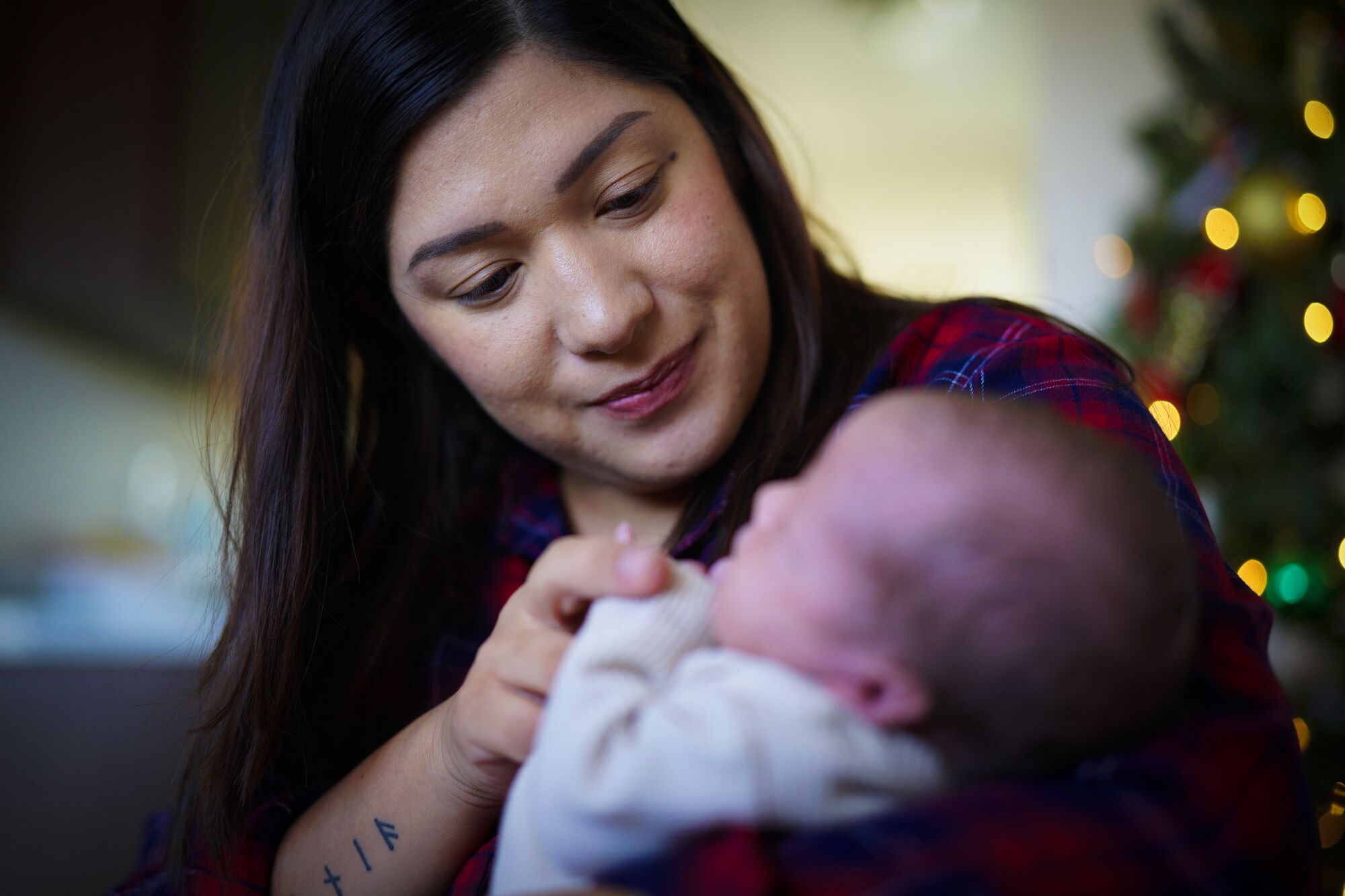 A woman smiles and looks down lovingly at the newborn she is cradling in her arms.