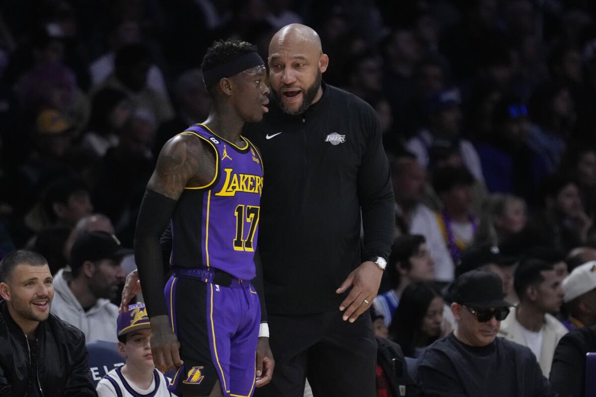 Lakers coach Darvin Ham, right, talks to point guard Dennis Schroder along the sideline during a break in play.