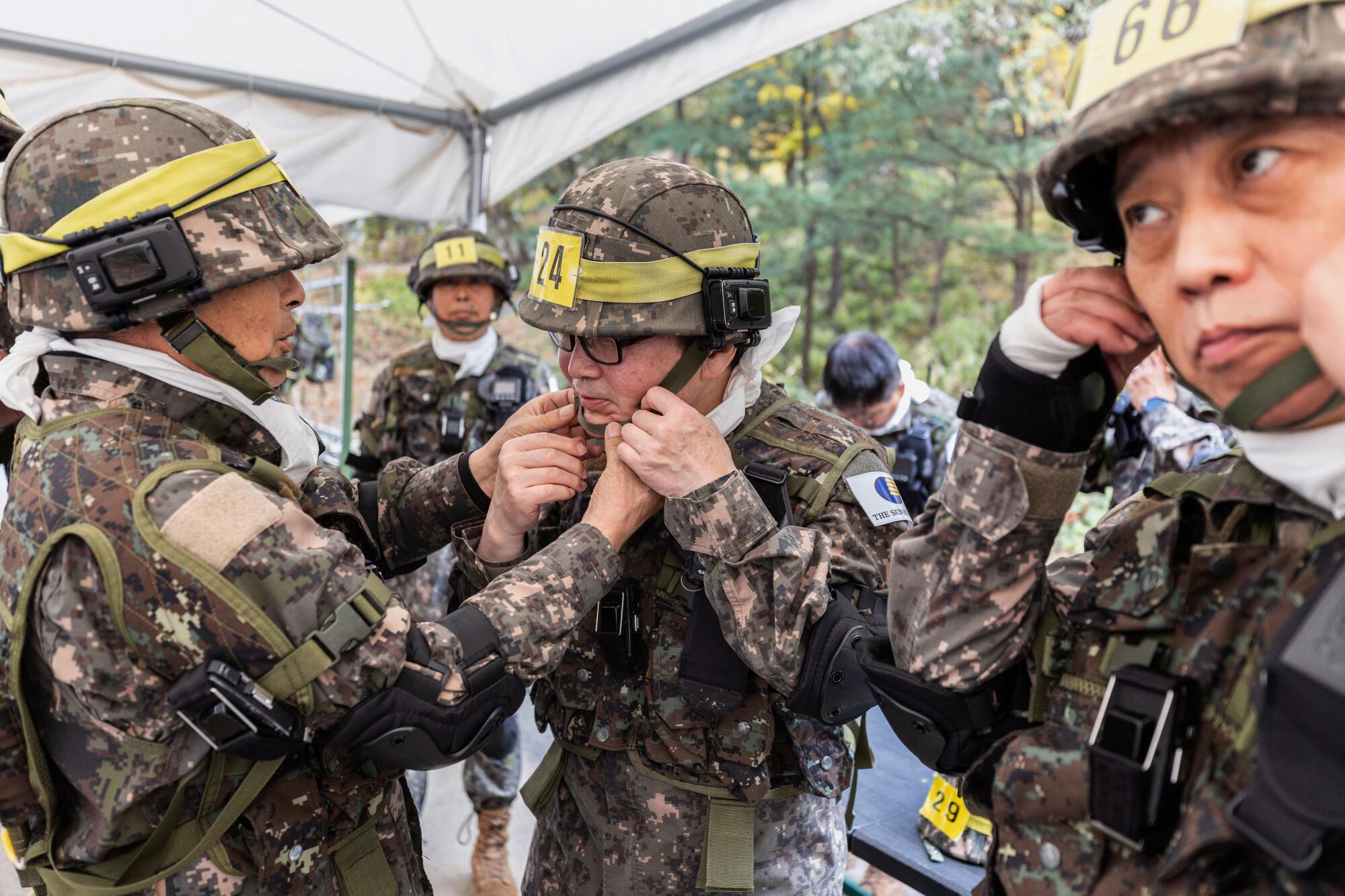 Members of the Senior Army help each other don protective gear during military training at the