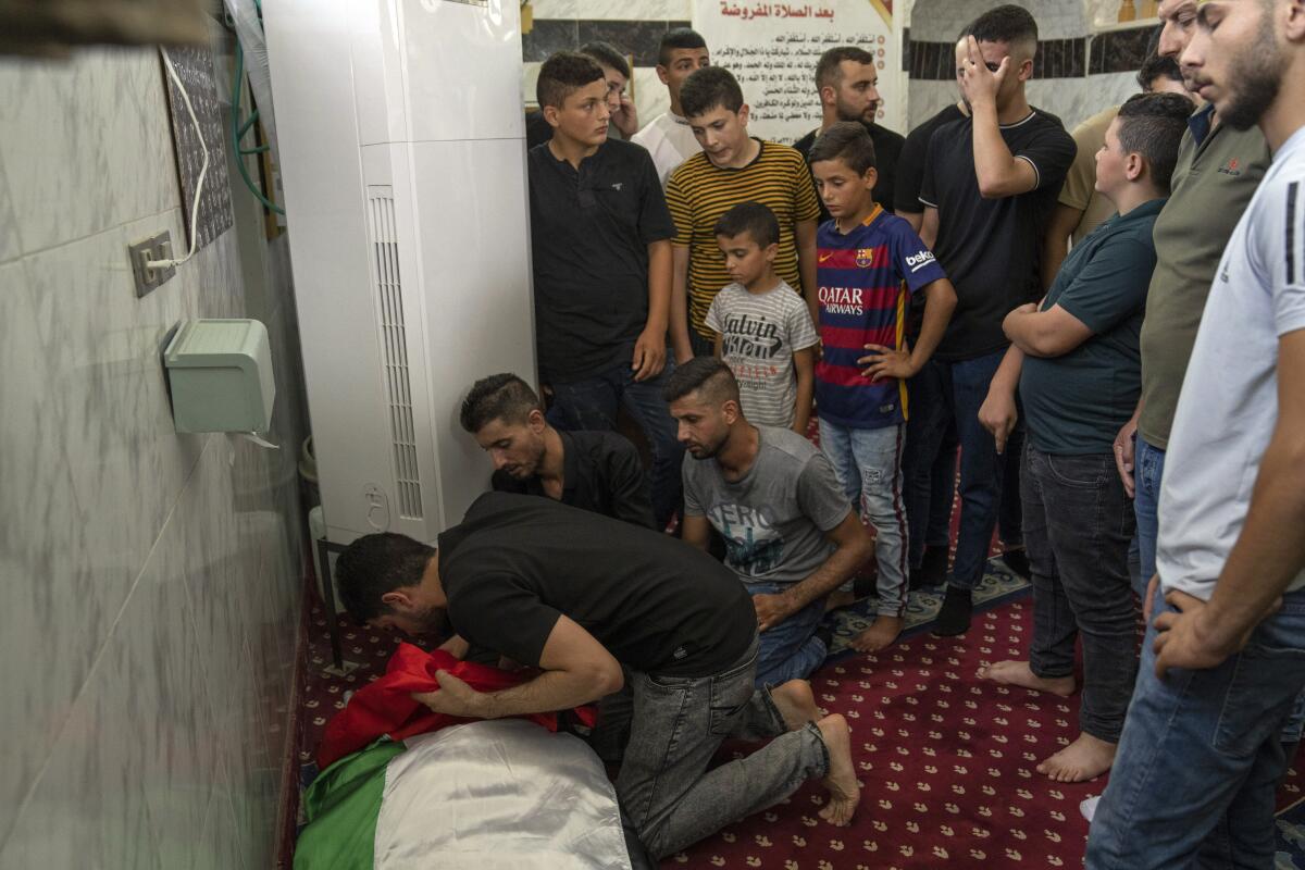 Grieving men and boys gather next to the body of a Palestinian man