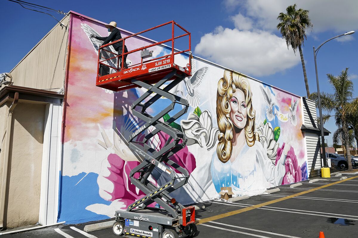 Long Beach-based artist David Gilmore works on a mural outside Strut Bar & Club.