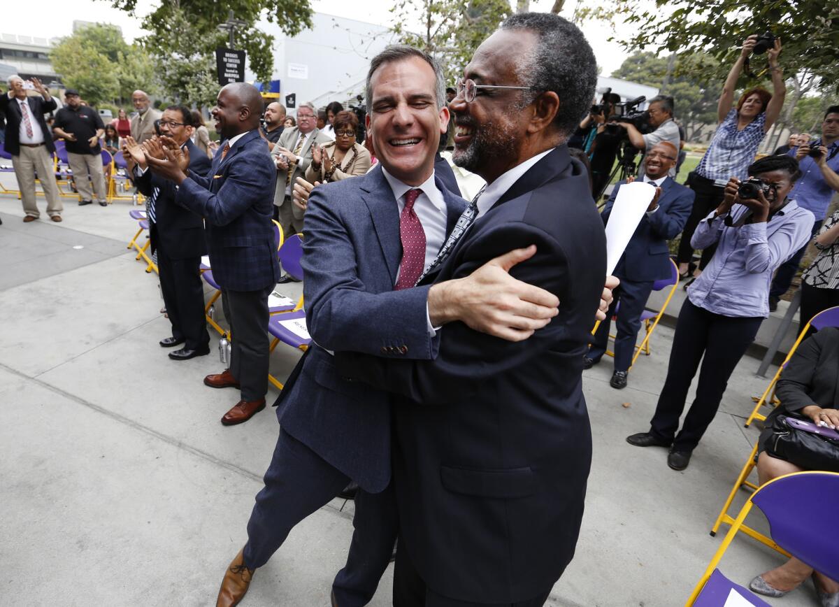 Los Angeles Mayor Eric Garcetti, left, hugs Councilman Curren D. Price, Jr., right, as Federal officials announce that South Los Angeles will be designated a promise zone.