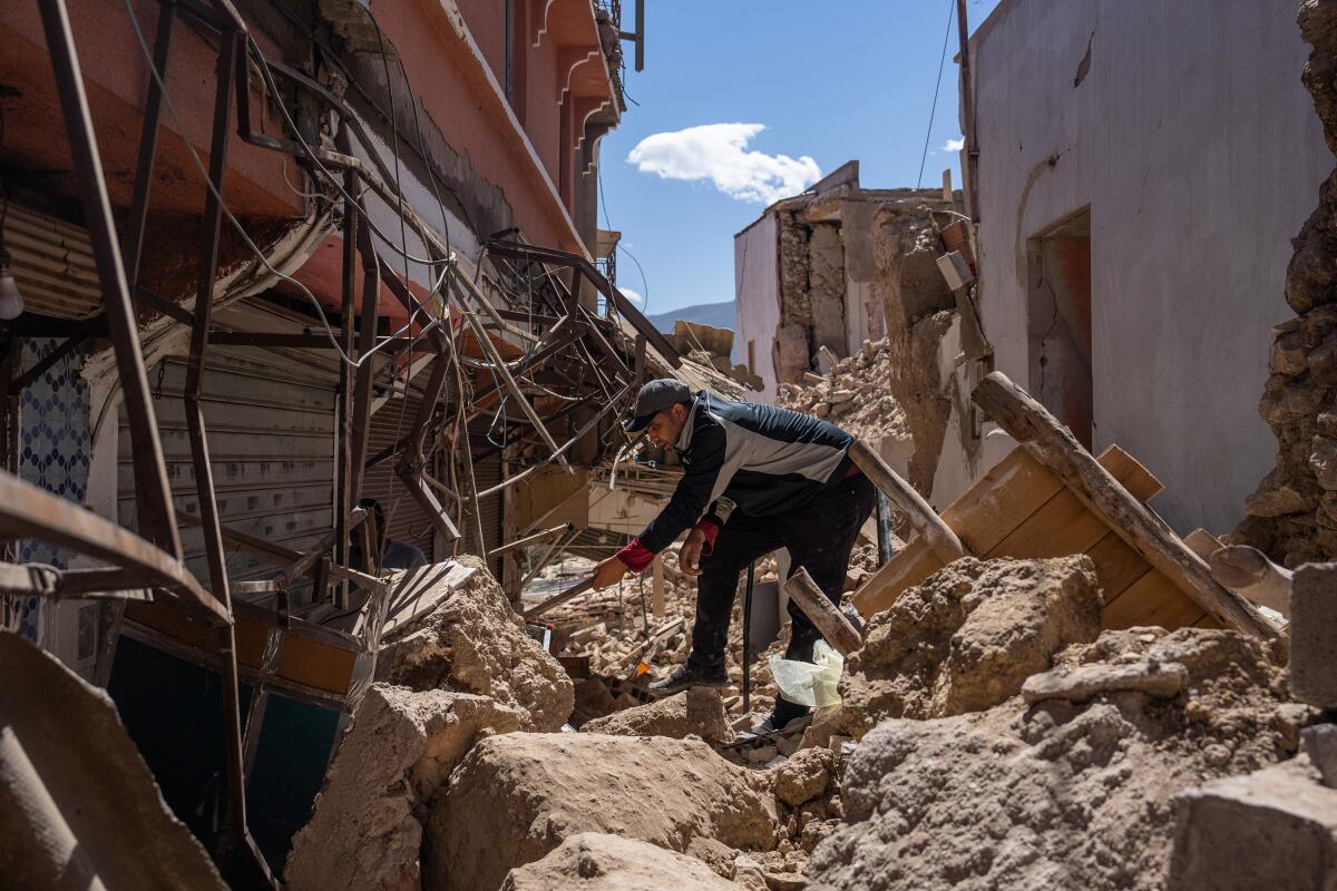 A man tries to get into a heavily damaged building while surrounded by the rubble of a building 
