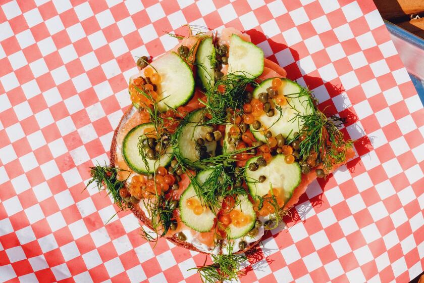 An overhead photo of gravlax-and-ikura smørrebrød with dill on red-and-white checkered paper at Piknik on Echo Park Lake.