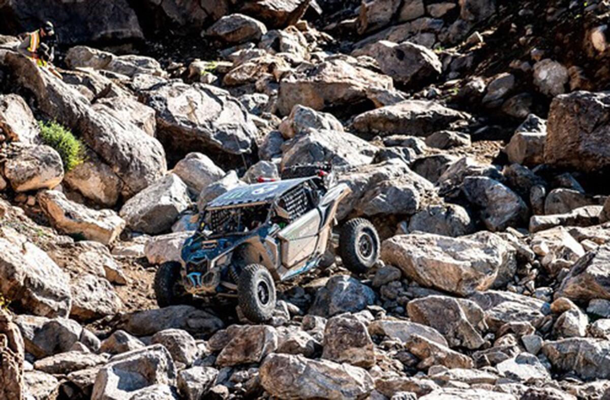 An off-road vehicle crawls over giant rocks. 