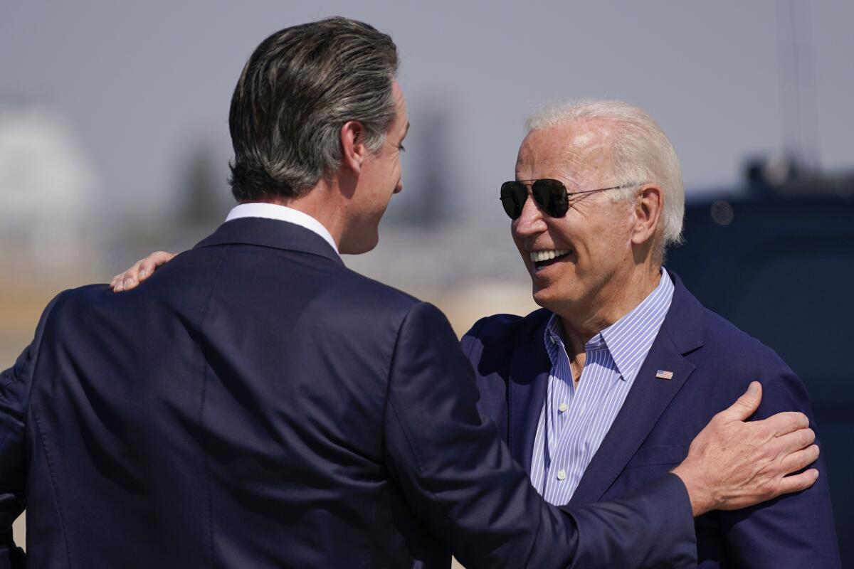 President Biden, wearing sunglasses, smiles as he greets Gov. Gavin Newsom at Mather Airport on Monday.