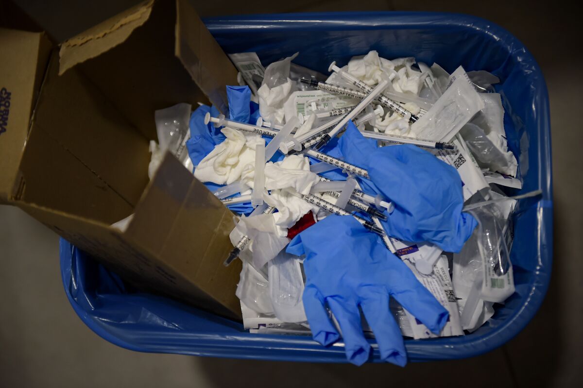 File---File photo show a view of a waste basket with syringes and gloves after residents received a dose of the third Pfizer COVID-19 vaccine, at San Jeronimo nursing home, in Estella, around 38 kms from Pamplona, northern Spain, Thursday, Sept. 23. 2021. The World Health Organization says overuse of gloves, “moon suits” and the use of billions of masks and vaccination syringes to help prevent the spread of the coronavirus have spurred a huge glut of health care waste worldwide. (AP Photo/Alvaro Barrientos)