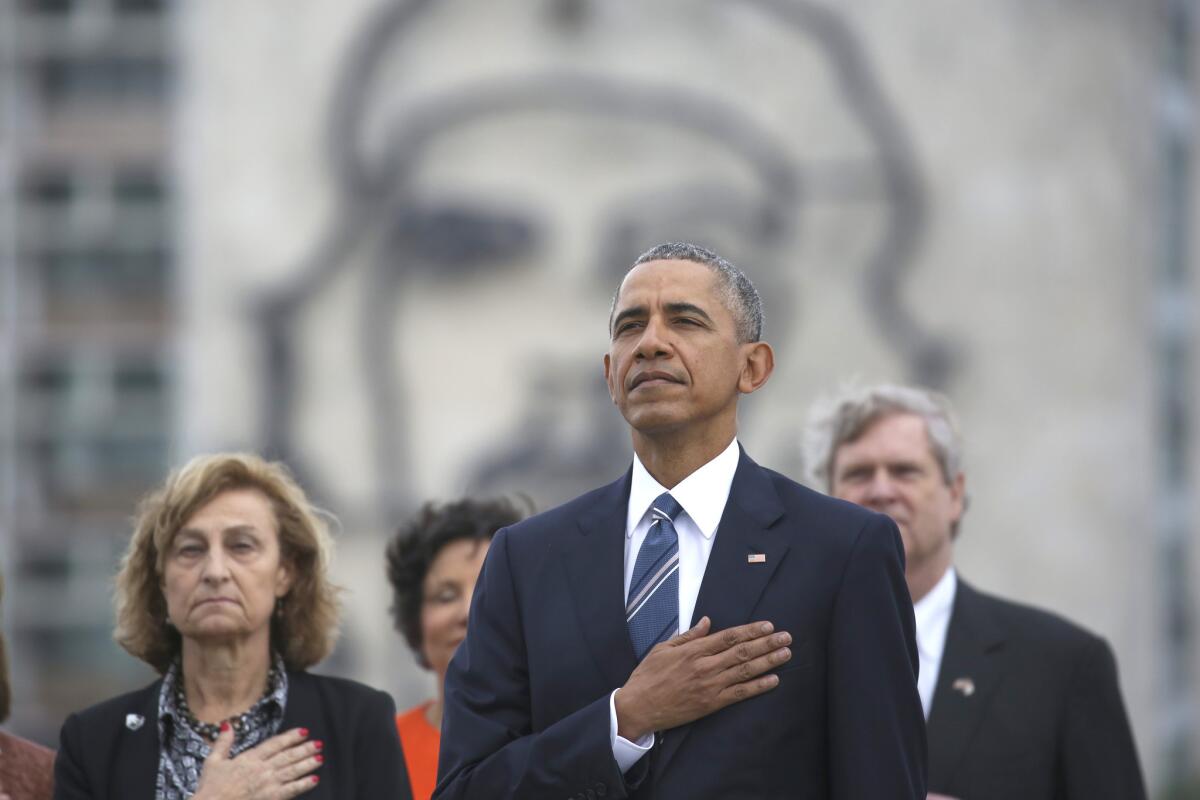President Barack Obama listens to the U.S. national anthem during a ceremony in Havana. He stands before a famous sculpture of Che Guevara by Enrique Avila Gonzalez.