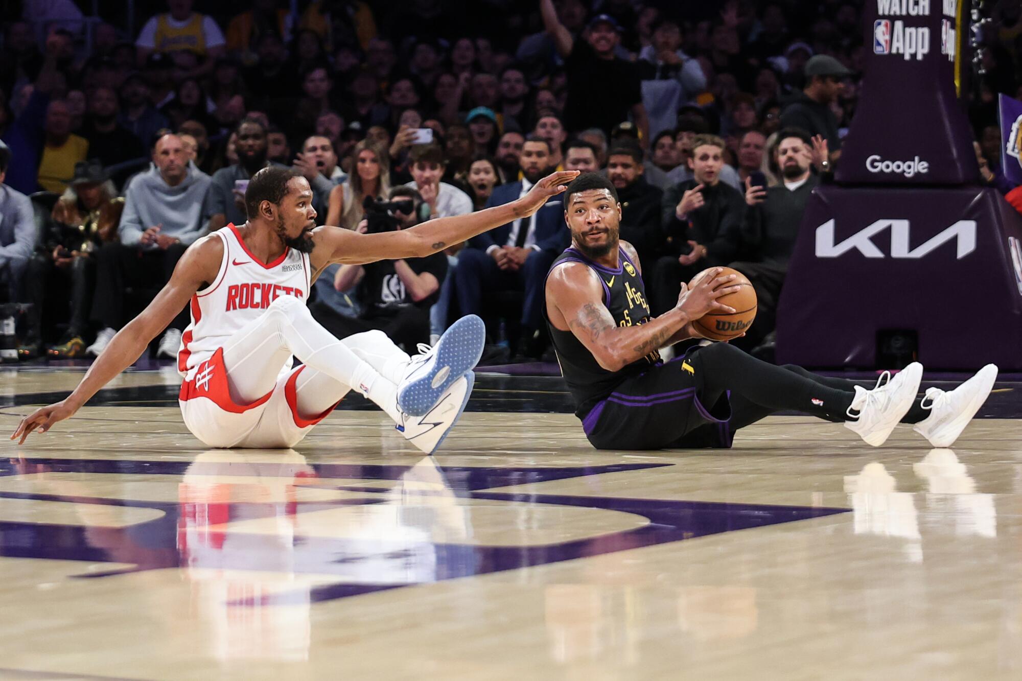Lakers guardı Marcus Smart, basketbol topunu Houston forveti Kevin Durant'ten uzaklaştırdıktan sonra elindeki topla birlikte yere oturuyor.