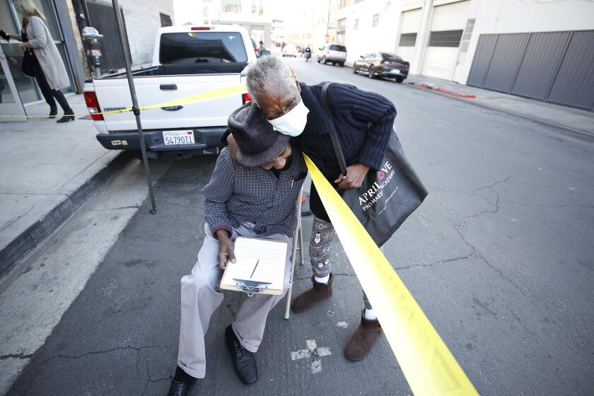 LOS ANGELES, CA - FEBRUARY 05: Cornelius Kincy, 69, hugs friend Fannie Mayfield before he receives a COVID-19 vaccination shot as healthcare staff at Los Angeles Christian Health Centers, Joshua House Clinic on Winston Street in the Skid Row area of downtown Los Angeles are administering COVID-19 vaccinations to their community member/patient's this Friday morning. Skid Row on {what} in Los Angeles, CA. (Al Seib / Los Angeles Times).