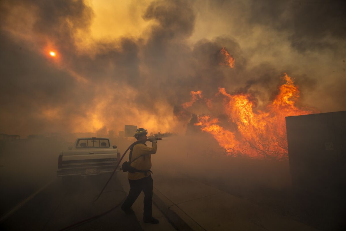 Firefighter Raymond Vasquez fights the Silverado fire fueled by Santa Ana winds at the 241 toll road