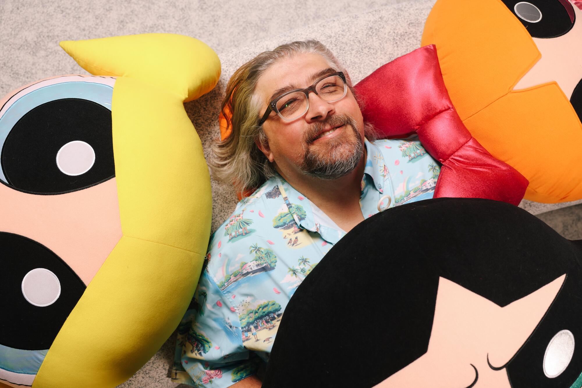 Craig McCracken surrounded by giant plushes of Bubbles, Blossom and Buttercup.