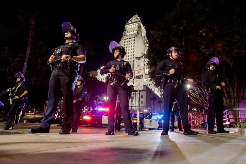 LOS ANGELES, CA - JANUARY 27, 2023: Los Angeles Police officers stand should to shoulder wearing riot gear near City Hall after crowds became unruly after a vigil for Tyre Nichols near LAPD on January 27, 2023 in Los Angeles, California. (Gina Ferazzi / Los Angeles Times)