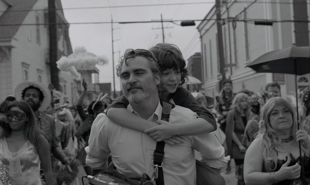 Joaquin Phoenix carries Woody Norman in "C'mon C'mon."