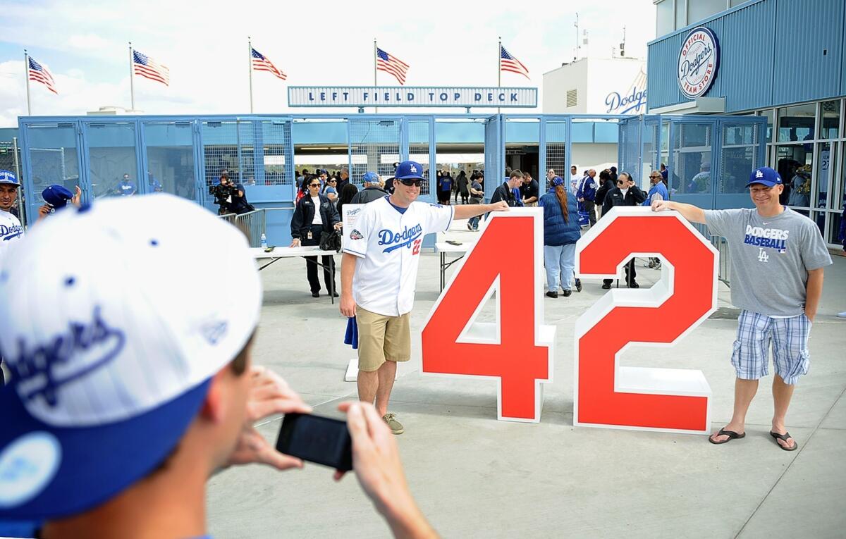 Dodgers fans Greg Webb and Greg Baker, right, take a photo with Jakie Robinson's retired number on Opening Day last year at Dodger Stadium.
