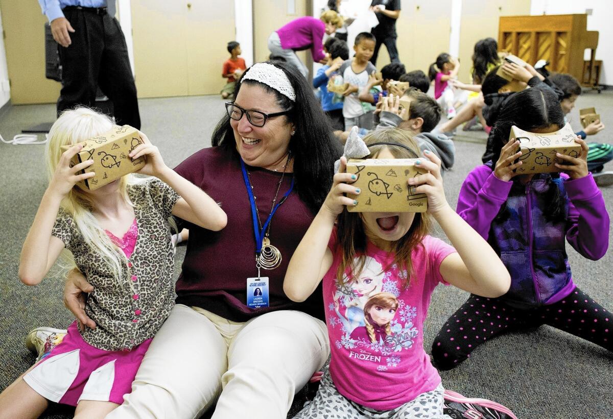 Lauren Brooks, PTA President and Irvine Children's Fund board member, sits with second graders Summer Wilson, left, and Kayla Hardy, second from right, as they participate in Google Expeditions Tuesday morning at Santiago Hills Elementary School in Irvine.