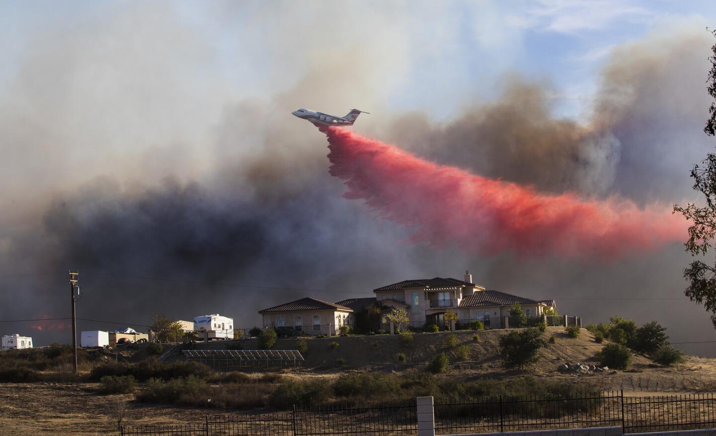 A plane drops fire retardant near a home to stop the wind driven Liberty Fire near Los Alamos Road.
