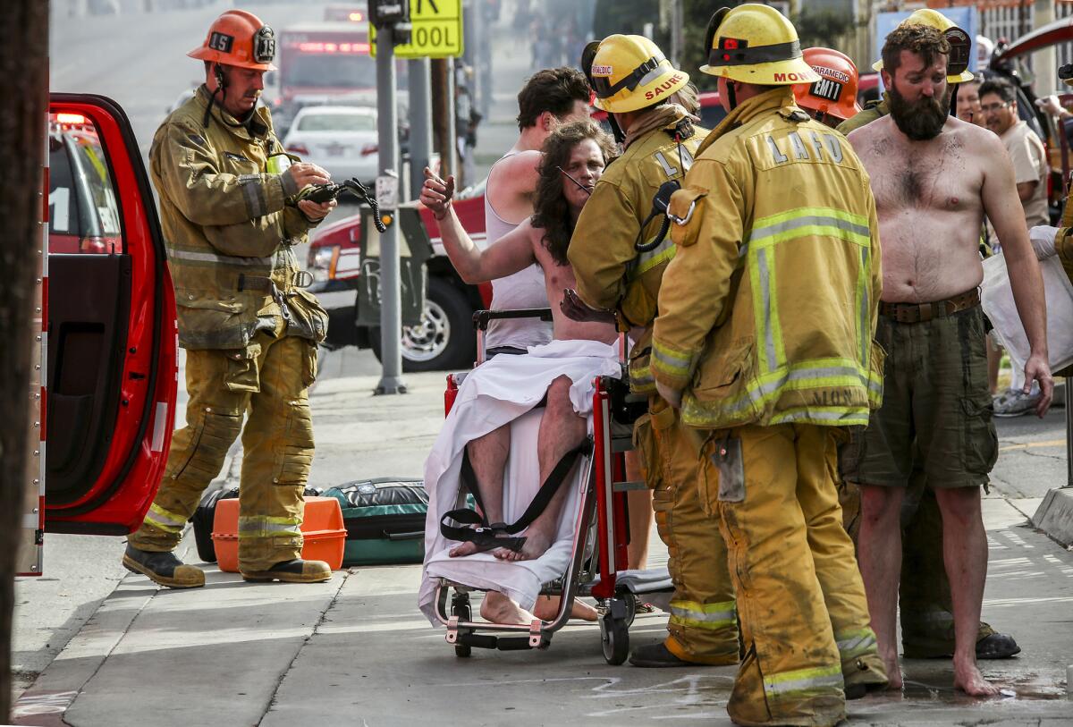 Firefighters tend to residents of a house that caught fire Saturday morning in Echo Park. One person was killed in the fire and several others were injured.