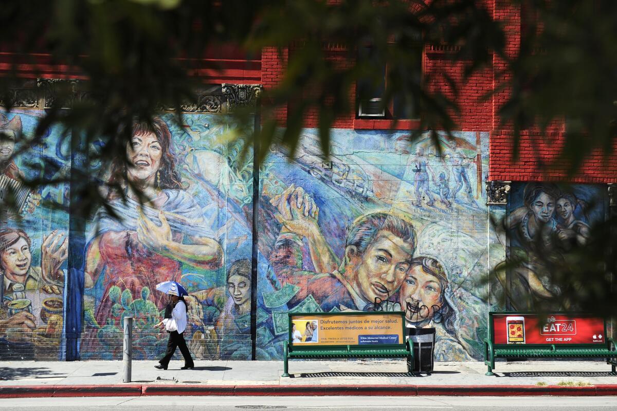 A pedestrian passes by a mural in Boyle Heights.