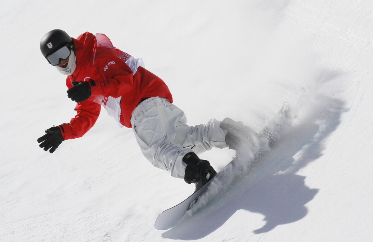 An Olympic snowboarder wearing cold weather gear practices at the Zhangjiakou Genting Snow Park.