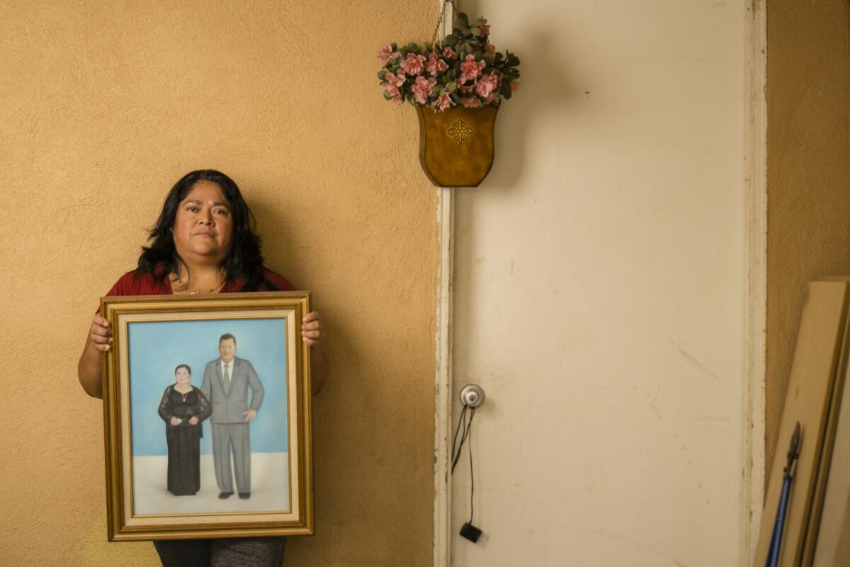 Rosario Rodríguez holds a picture of her parents, Herminia and Martin Rodriguez, in her garage in Three Rocks, Calif.