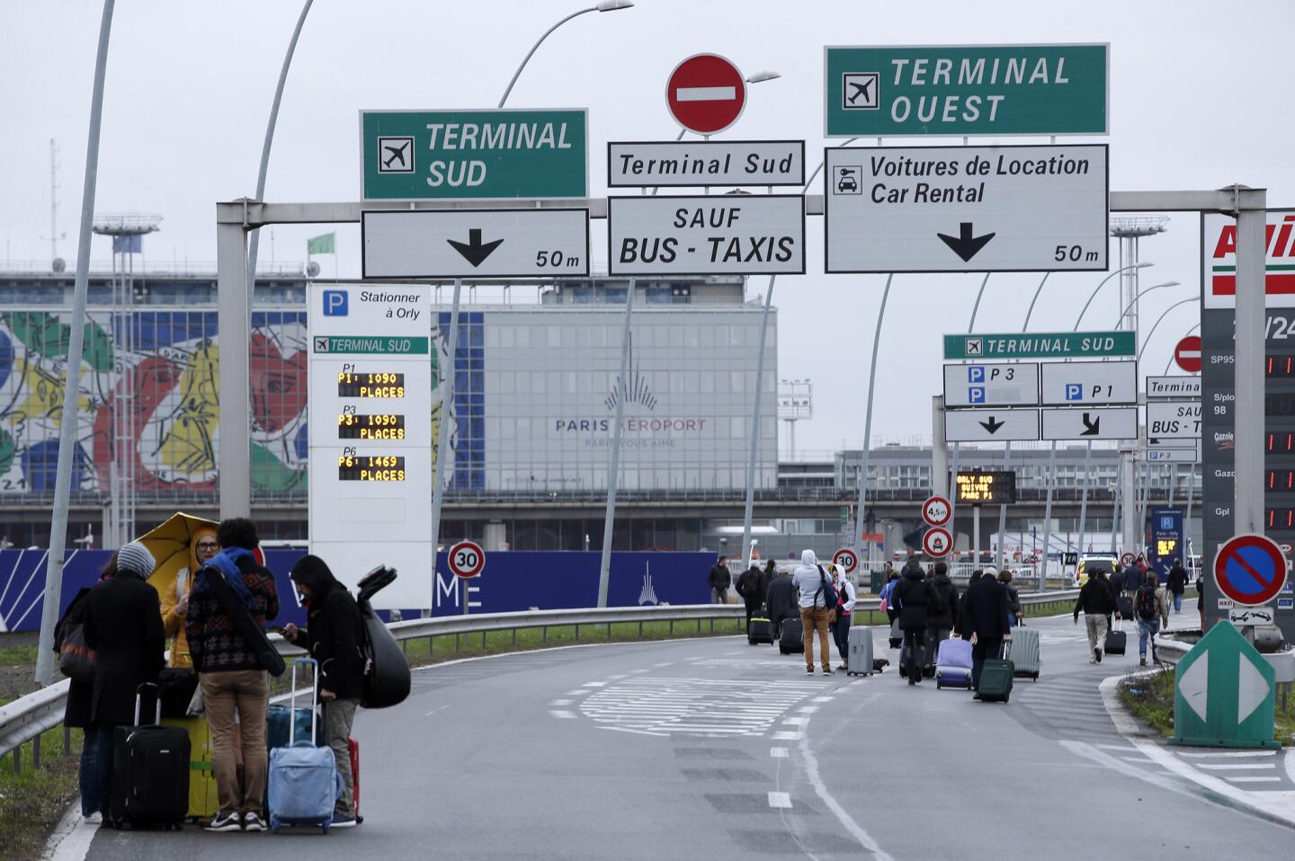 Viajeros caminan por la autopista que llega al aeropuerto de Orly, al sur de París, el sábado 18 de marzo de 2017. Un hombre murió baleado en el aeropuerto tras arrebatar un fusil a una soldado que protegía el lugar, según la policía, lo que provocó una evacuación parcial de la terminal. (AP Foto/Thibault Camus)