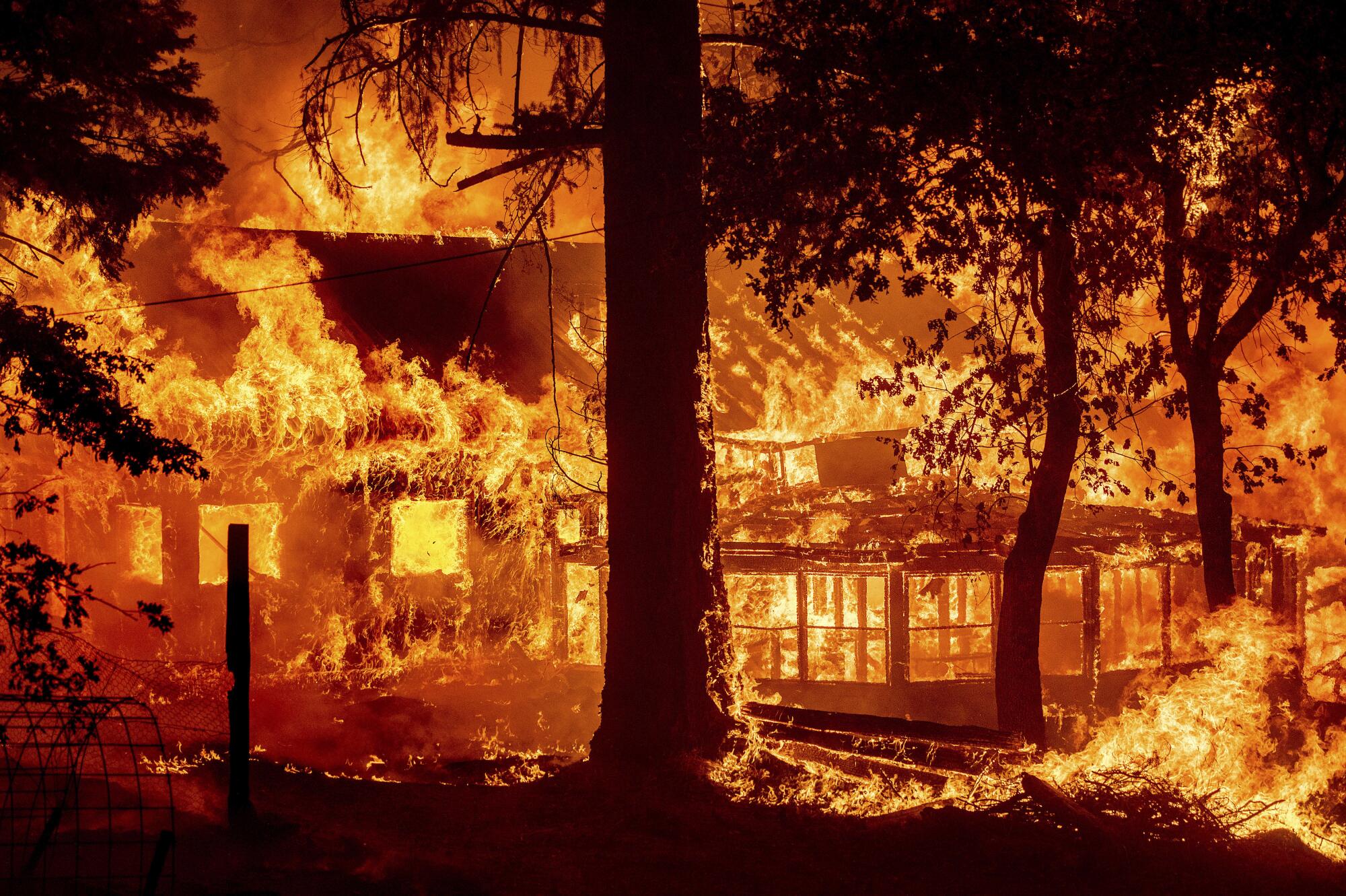 Flames from the Dixie fire consume a home in the Indian Falls community of Plumas County, Calif.