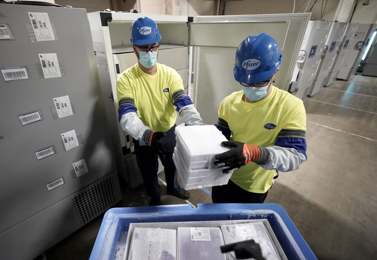 Two workers hold boxes containing the Pfizer-BioNTech COVID-19 vaccine at a manufacturing plant in Portage, Mich.