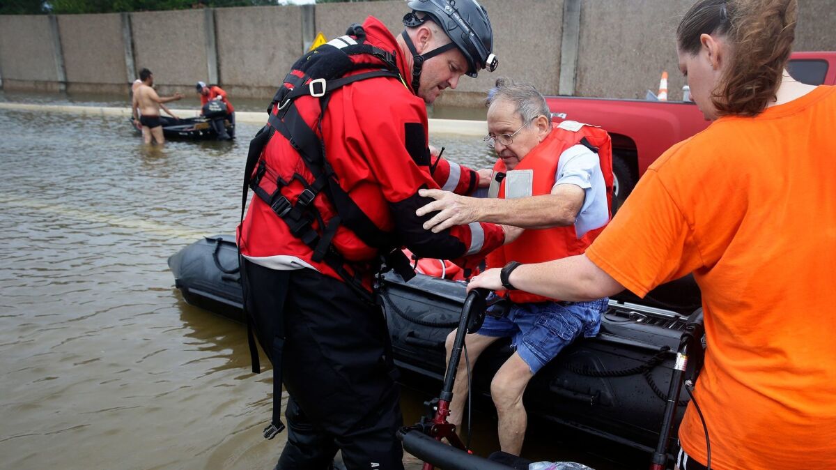 A Houston Police Department officer helps Frank Andrews, 74, into his walking chair after rescuing him from his flooded home in the Braeswood Place neighborhood southwest of Houston. (Robert Gauthier / Los Angeles Times)