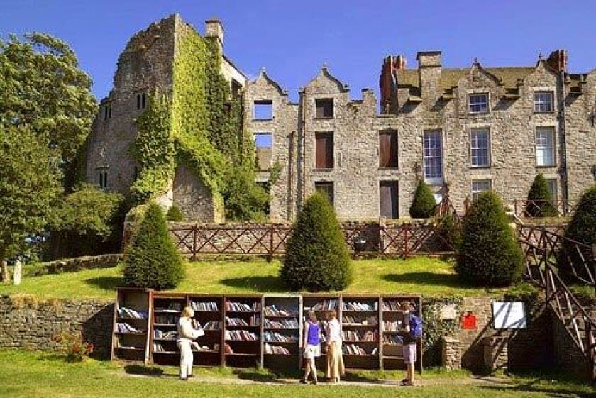 The walls of Hay Castle provide a backdrop for browsers at an outdoor bookshop.