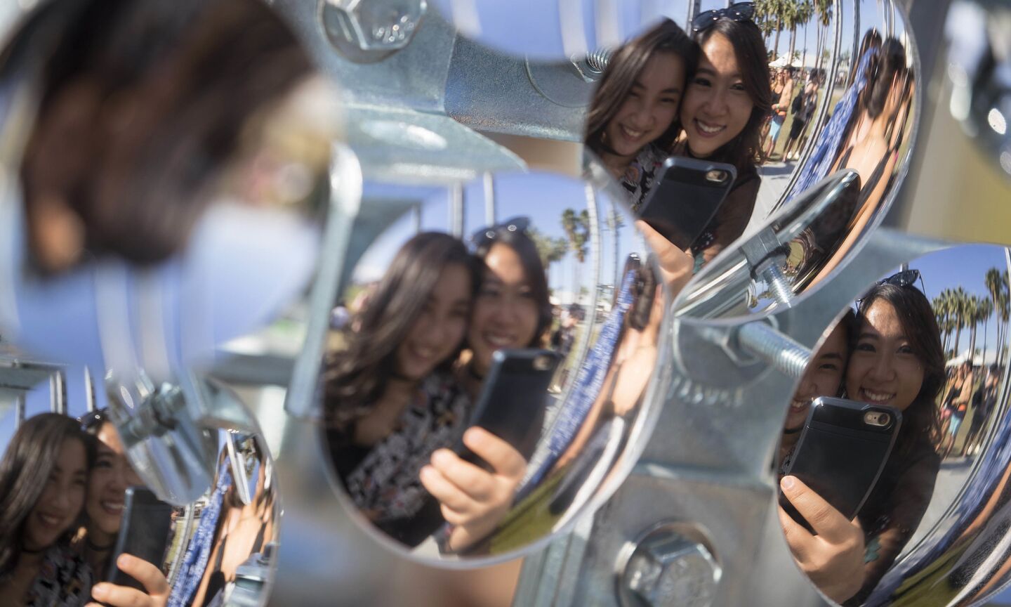 INDIO, CALIF. -- FRIDAY, APRIL 14, 2017: Coachella goers Lexi Tuitan, 22, right, and sister Pia Tuitan, 20, of Manila take photos at the art installation 'Lamp Beside the Golden Door'at the Coachella Music and Arts Festival in Indio, Calif., on April 14, 2017. (Brian van der Brug / Los Angeles Times)