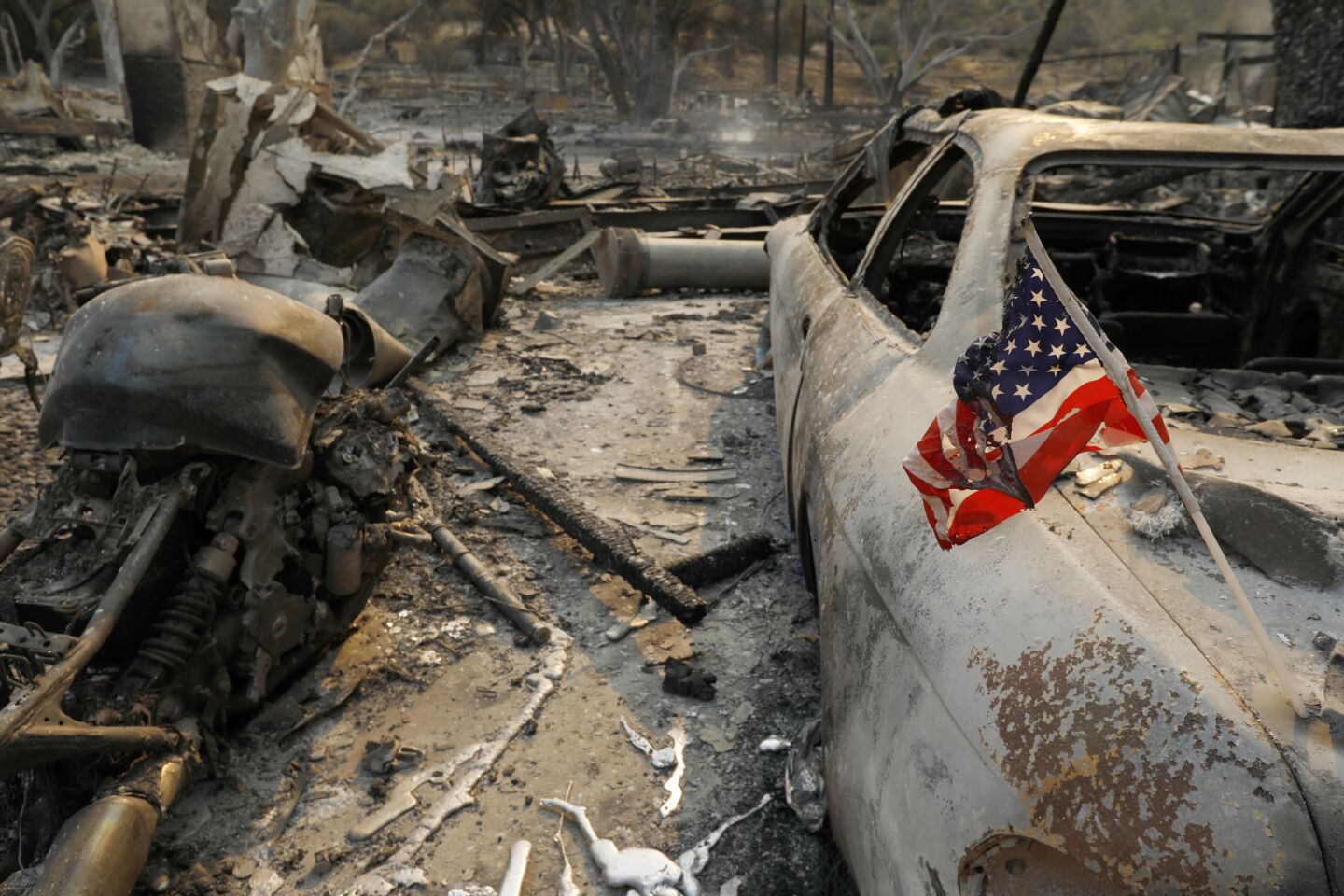 An American flag is melted on a burned-out car on property in a mobile home park in Westlake Village.