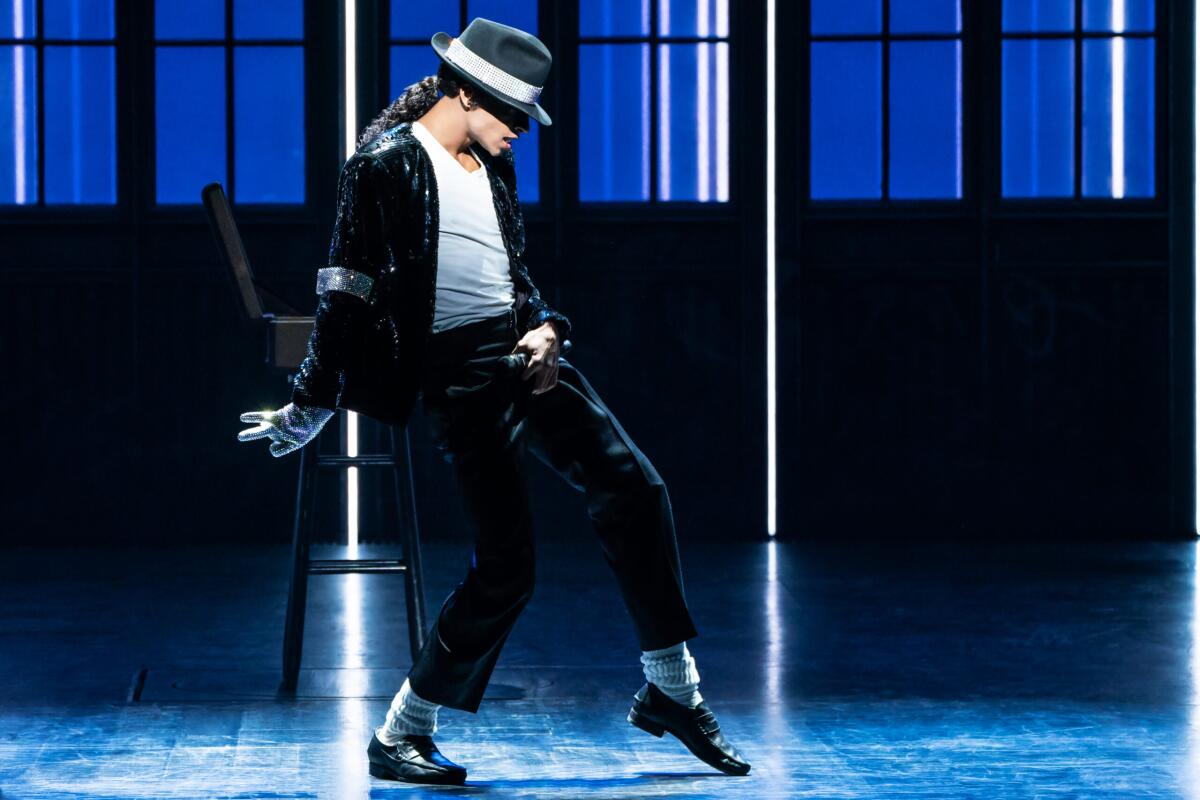 A performer in a black fedora, white T-shirt, penny loafers and one sequined glove strikes a pose onstage.