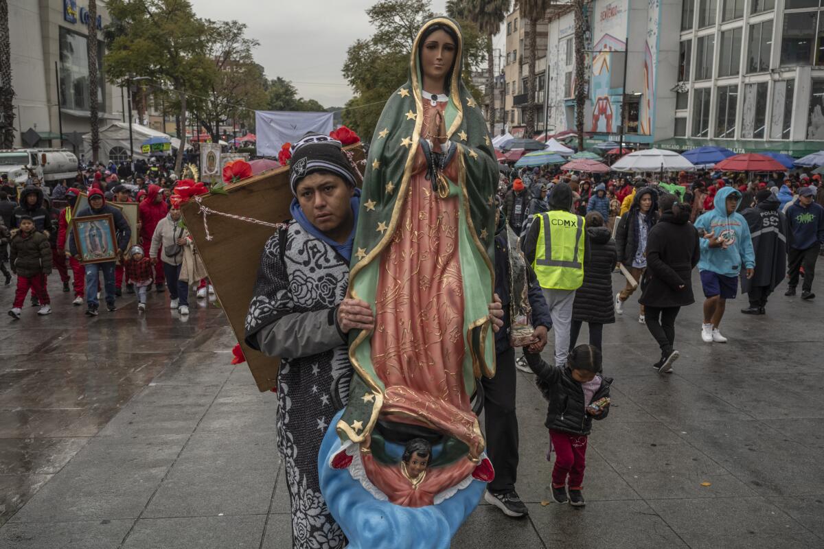 A man carries a figure of the Virgin of Guadalupe