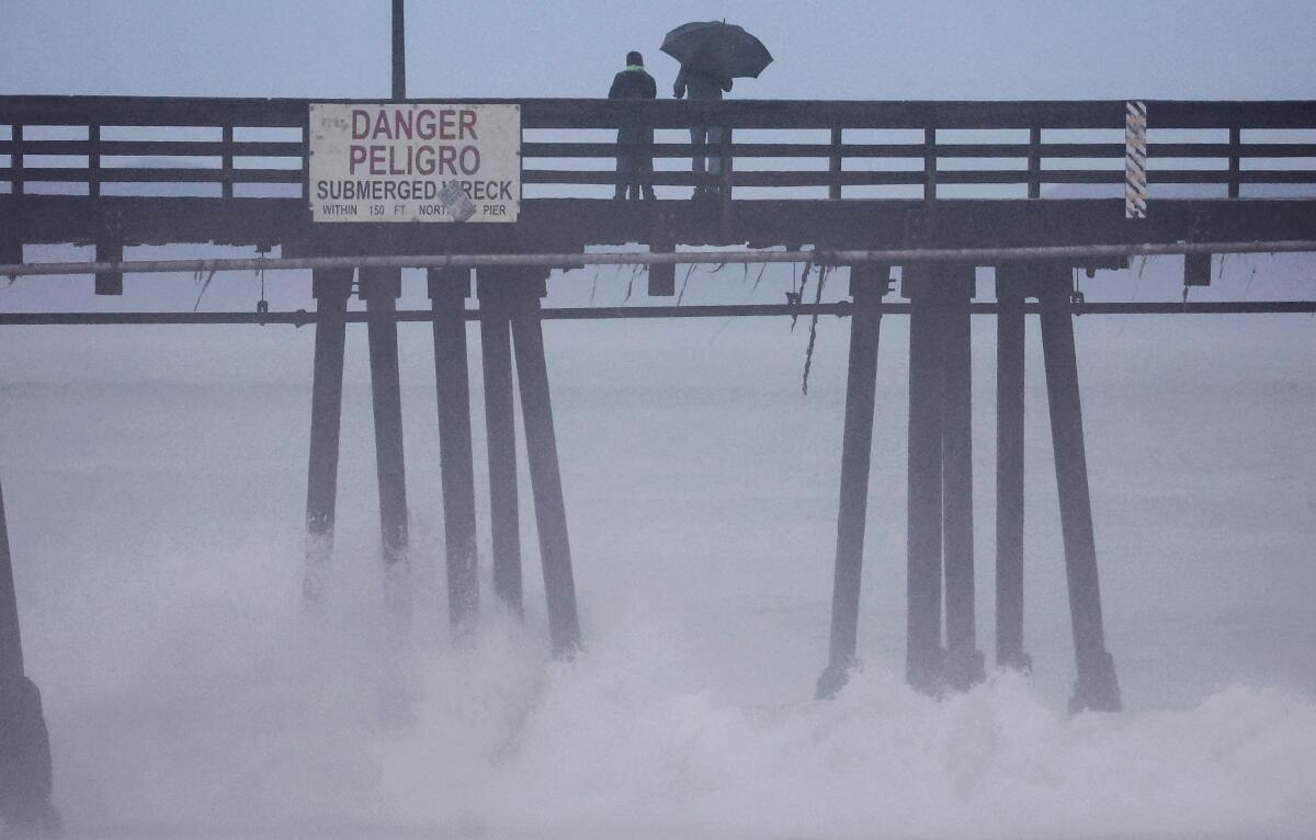 People stand on a pier in the rain.